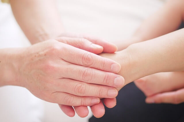 A mans hands holding a woman's hand.