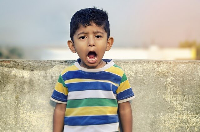 Little boy with his mouth open wide, illustrating how large of an object can pose a choking risk.