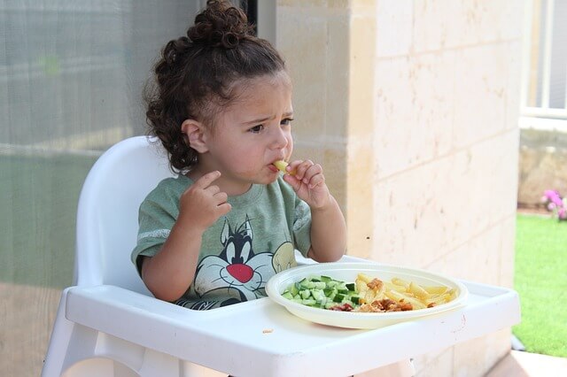 Little girl eating in a highchair to prevent choking.