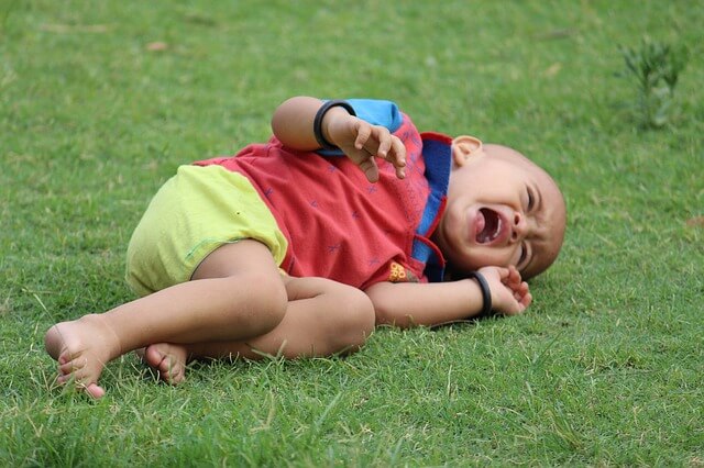 Young child laying on the ground in distress, unable to clear a choking obstruction by coughing.