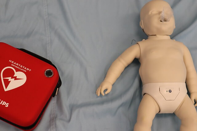 Doll and First Aide box for practicing CPR on unresponsive child.
