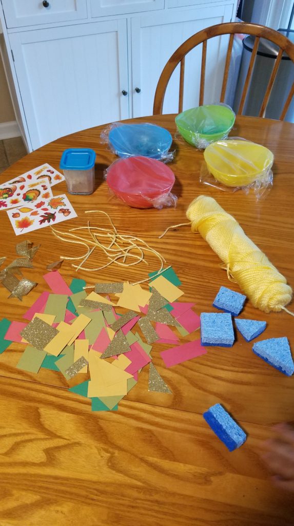 Paints and crafting items laid out on a table in preparation of carving a pumpkin with a toddler.