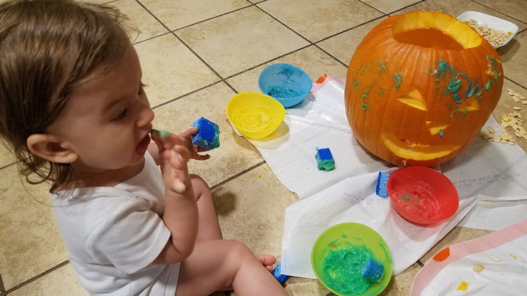 Mama Rissa's toddler tasting the paint she is using to decorate her pumpkin.