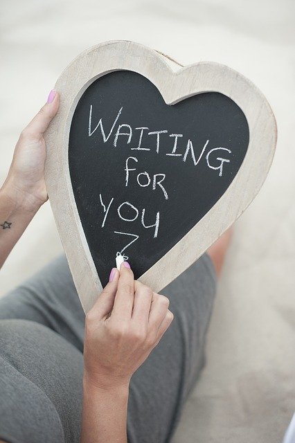 Pregnant woman writing "waiting for you" on a chalkboard. 