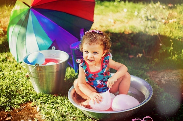 Toddler girl in a swimsuit playing with waterballoons