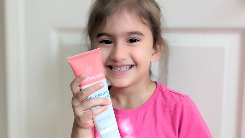 Mama Rissa's daughter holding tube of Wellnesse toothpaste